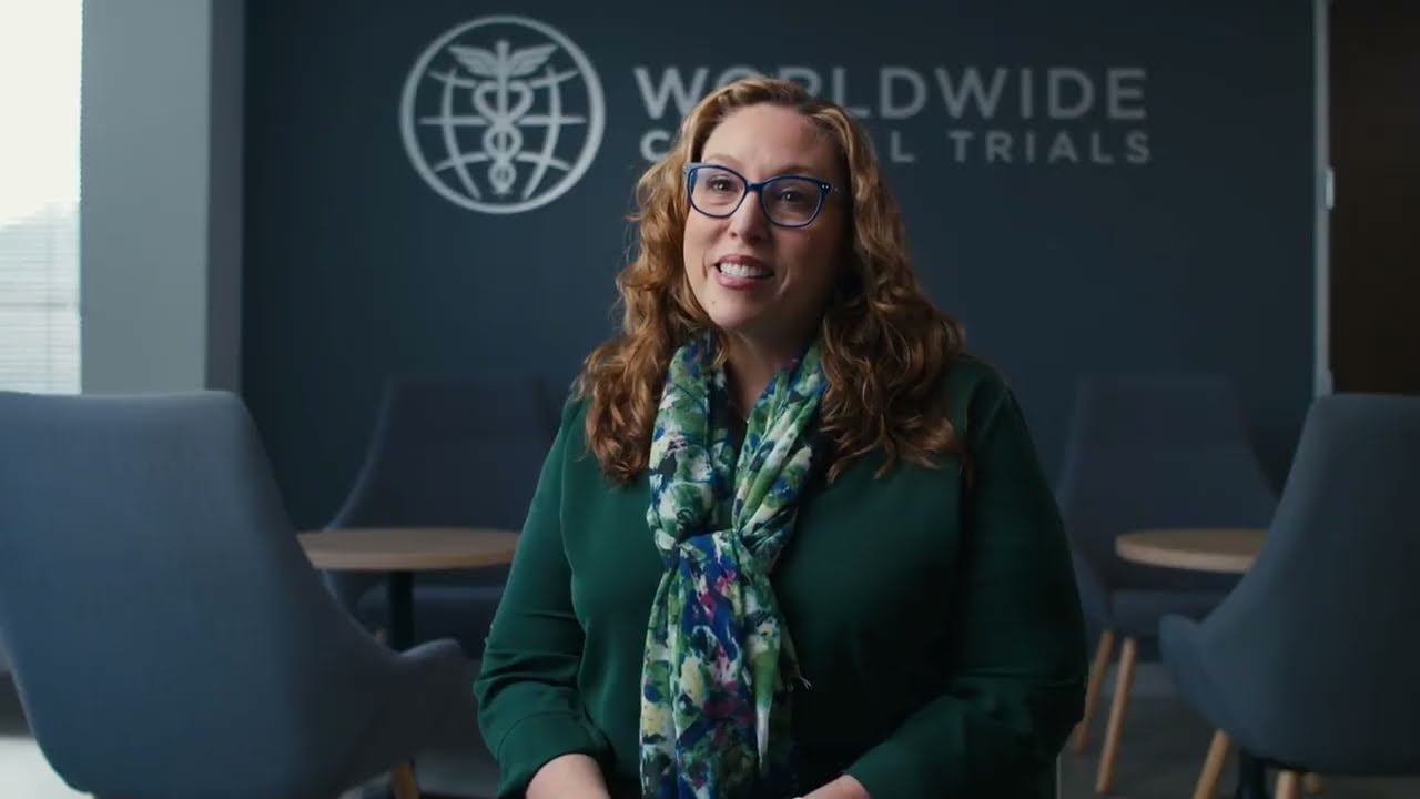 Play the film: a Worldwide Clinical Trials employee speaking to camera in front of the company logo wall